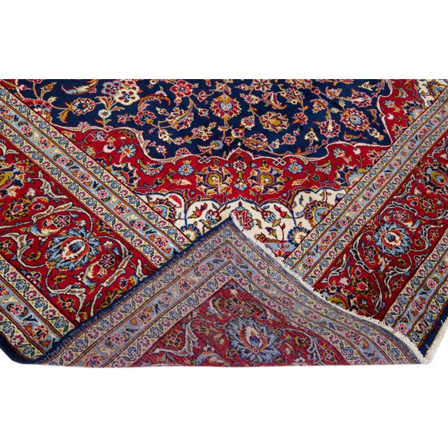 Beautiful antique Kashan hand-knotted wool rug with a navy blue color field. This Persian rug has a rusted frame and...