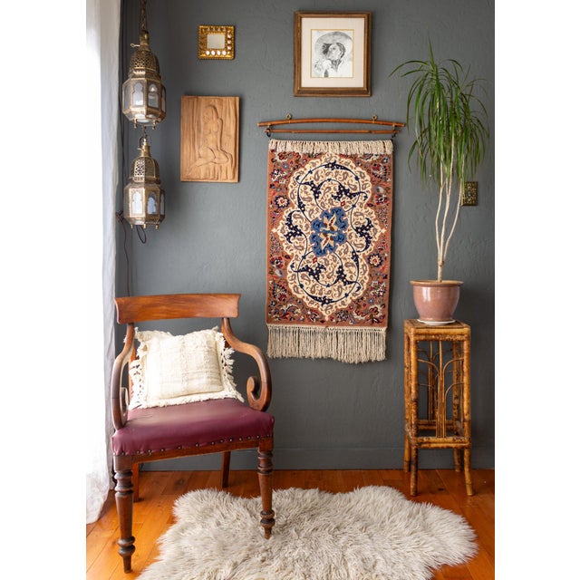 A 1970's Persian Isfahan wall hanging is hand-knotted from wool and silk, creating a finely detailed Arabesque motif which...