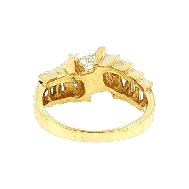 A late 20th-century twist ring featuring an emerald-cut white diamond, weighing approximately 1.0 carat. It is flanked by...