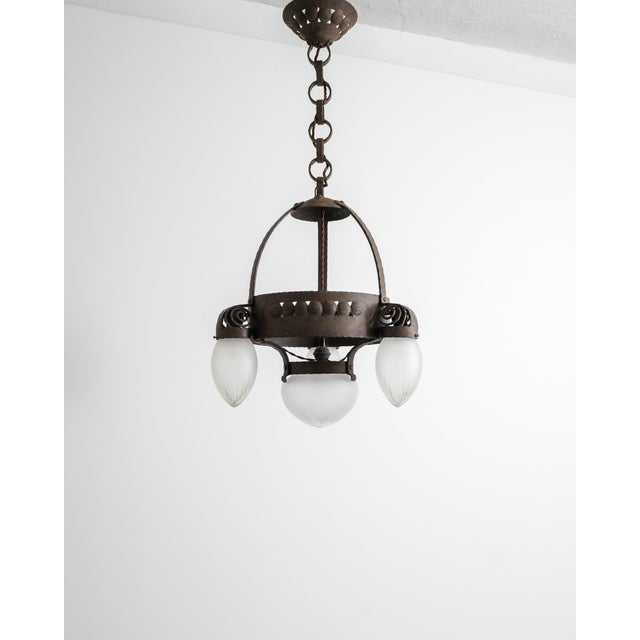 A rare and early Swedish jugend ceiling lamp in patinated and iron with four decorative and sculptural frosted glass...
