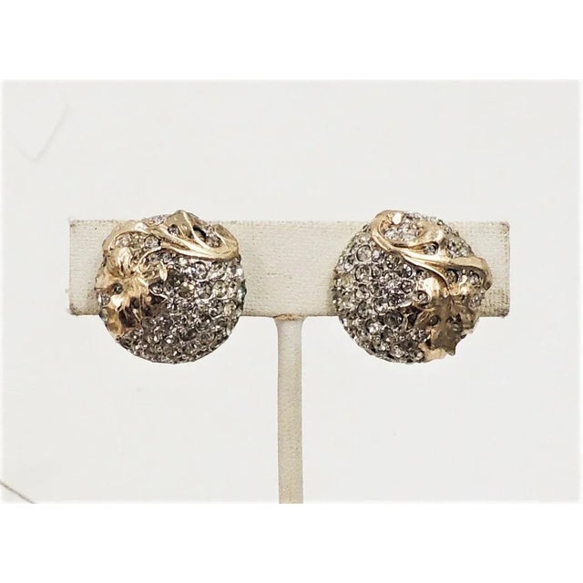 This is part of Chairish’s Costume Jewelry assortment. Circa early 1950s round goldtone pave clear rhinestone leaf clip...
