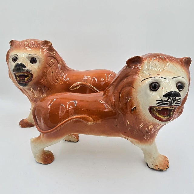 A pair of Staffordshire striding lions, repaired.