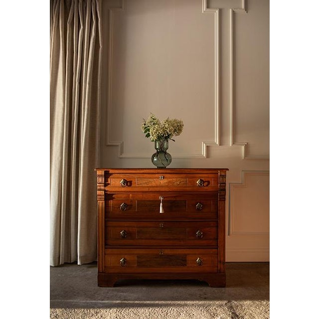 This American walnut chest of drawers dates to circa 1880. Heavily influenced by Neoclassical design, it features rich...
