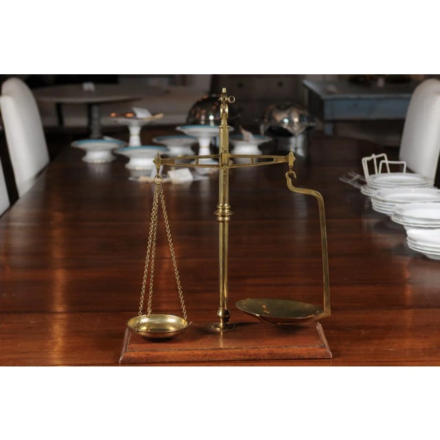 A French brass freestanding tea scale from the 19th century mounted on a wooden base. Born in France during the...