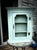 vintage wooden cabinet, upcycled with a light sage green or duck-egg blue paint finish. It features a single door with a...