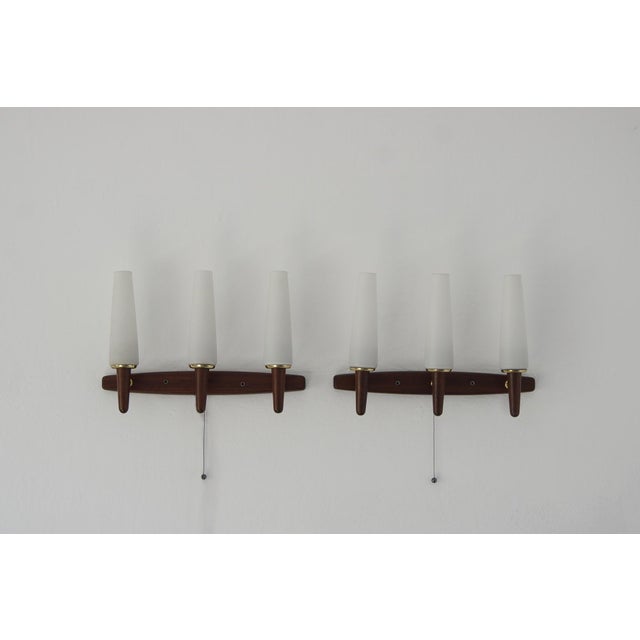 A modern set of Danish wall sconces in rosewood and opal glass made in the 1960s. The design includes a back with rosewood...