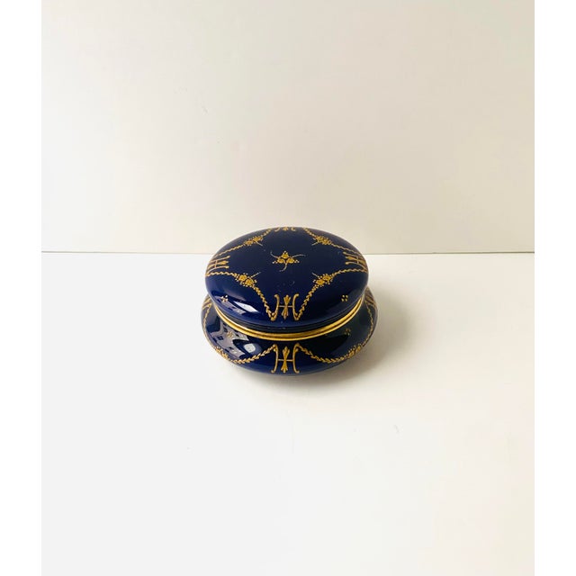 An elegant dark blue round porcelain jewelry box with raised gold gilt decoration, Neoclassical design style, circa...