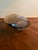 A striking hand-blown art glass vase featuring a sculptural oval form with a distinctive pierced center opening. The glass...