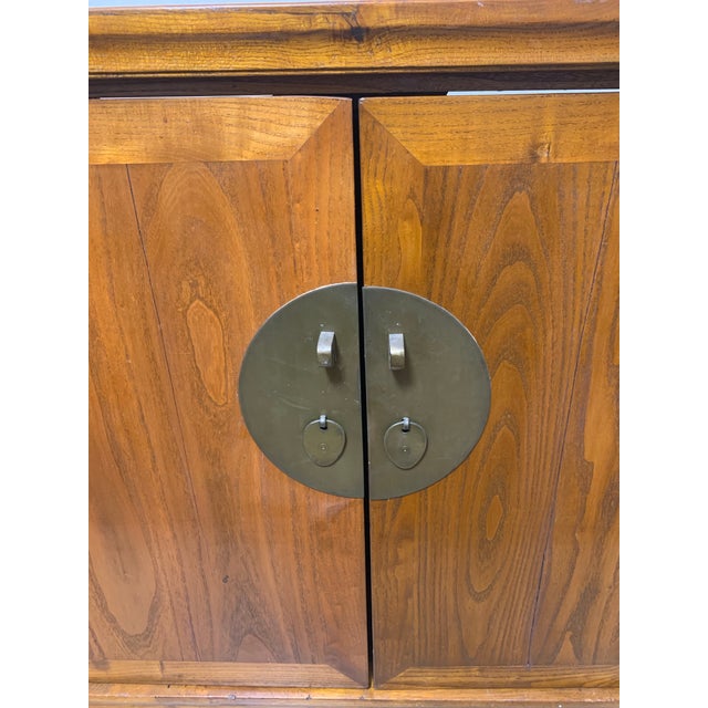 Beautiful vintage Asian-style wood cabinet featuring a warm natural wood finish, two raised-panel doors, and distinctive...