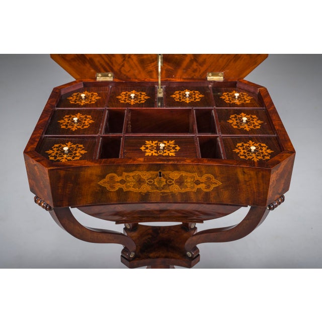 An elegant Biedermeier sewing work table crafted in richly figured mahogany and decorated with fine marquetry inlay,...