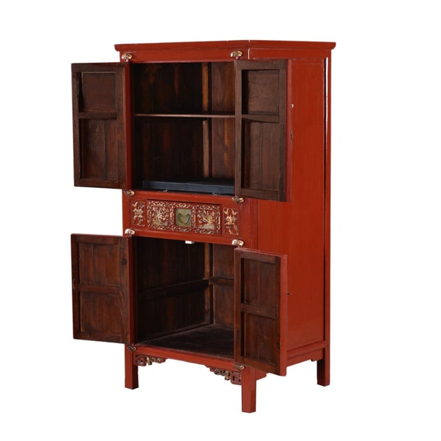 Hand carved chinoiserie style motifs adorn this substantial red lacquered armoire. Accented by brass metal hardware, the...