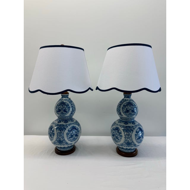 A sophisticated pair of Ralph Lauren Home double-gourd table lamps featuring classic blue and white porcelain bodies...