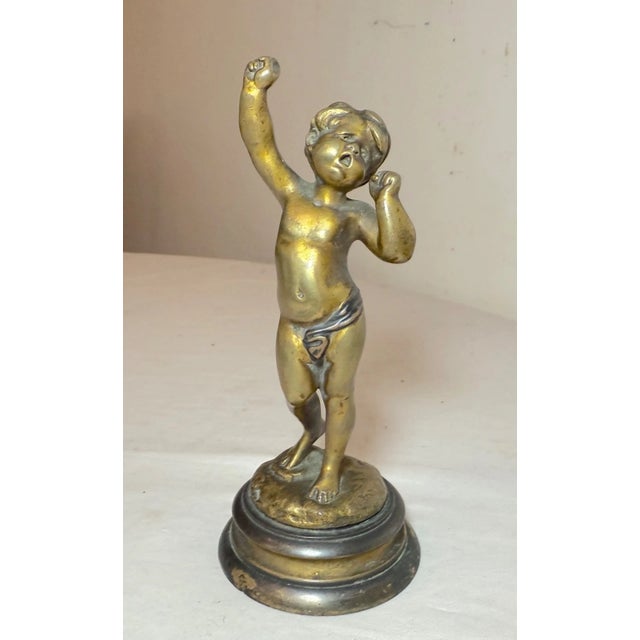 This antique patinated and gilt bronze depiction of cupid yawning statue is a beautifully crafted piece from the mid to...
