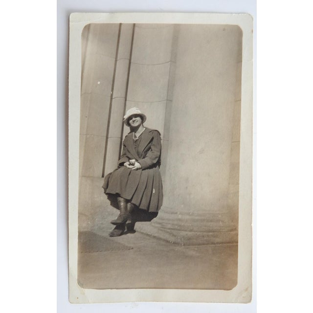 Early 20th century silver gelatin snapshot photograph of woman sitting at the base of large columns. Unframed, corner bumps.