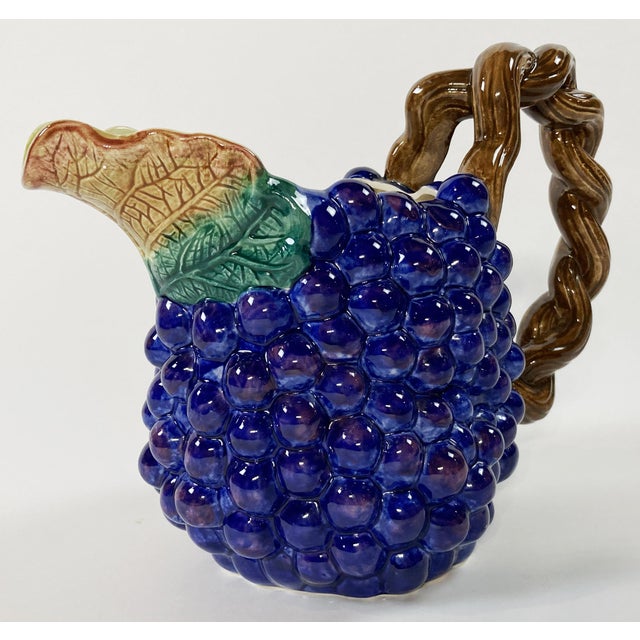 Whimsical brightly colored Fitz and Floyd ceramic 1.5 quart pitcher. Deep violet grape pattern with leaf spout and twisted...