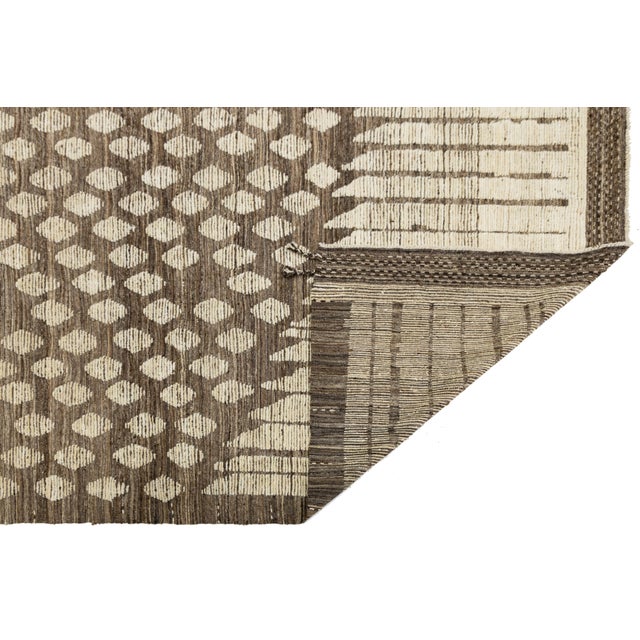 Handwoven in soft wool, this modern Moroccan-style rug features bold geometric contrasts in warm neutrals and crisp white....