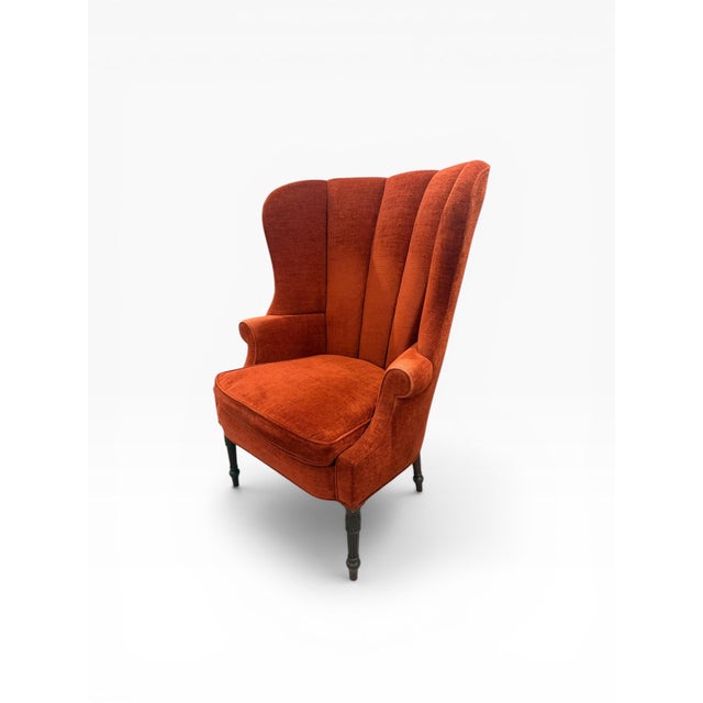 A beautifully proportioned wingback accent chair upholstered in a rich rust-toned fabric, offering warmth, depth, and...