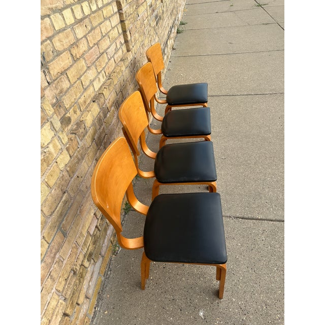 A set of four sturdy, commercial-grade bentwood chairs made by Falcon Products, Inc. Featuring a sleek, Mid-Century Modern...