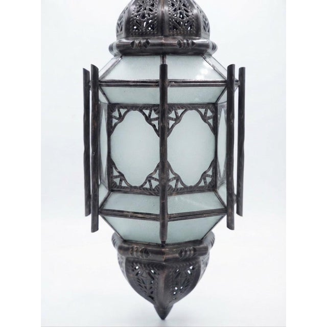 A handmade eight-sided lantern made from iron with an aged bronze finish and eight panels of gray frosted glass. The...
