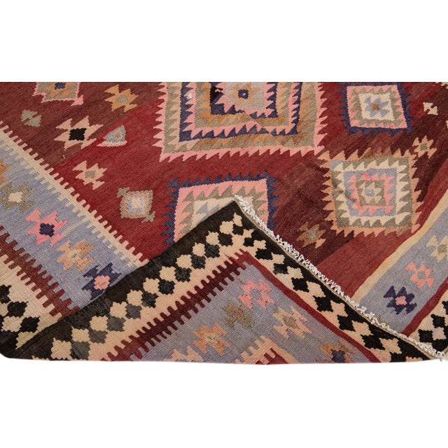 Beautiful vintage Turkish Kilim hand-knotted wool rug with a red field. This piece has multicolor accents in an all-over...