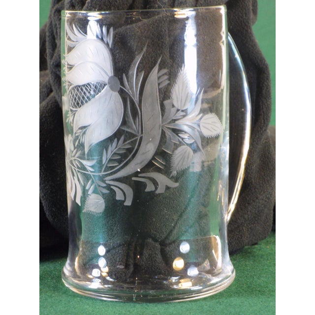 This item is a hand-worked flint glass beer stein with wheel engraving in the style of Stiegel, Germany. It is a copy of a...