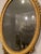 A George III oval giltwood mirror, late 18th century The urn shaped finial centered on foliate swags the oval frame with...