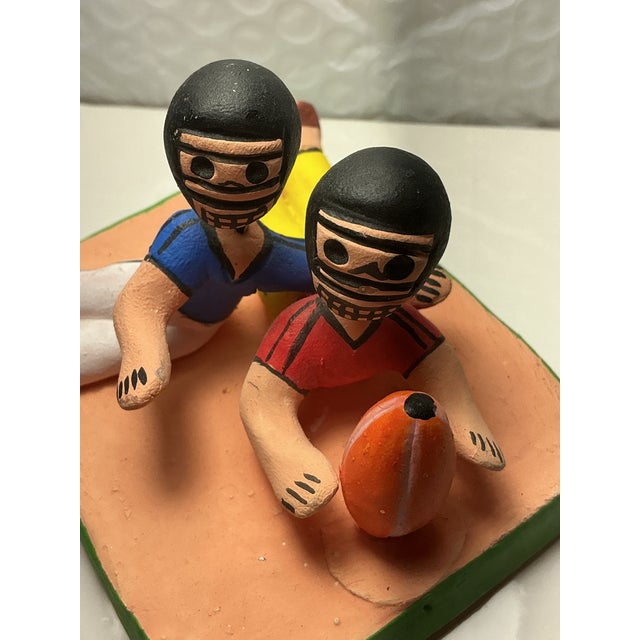 This is a piece of Mexican folk art, crafted from terracotta clay. The figures resemble traditional Ocumicho style...