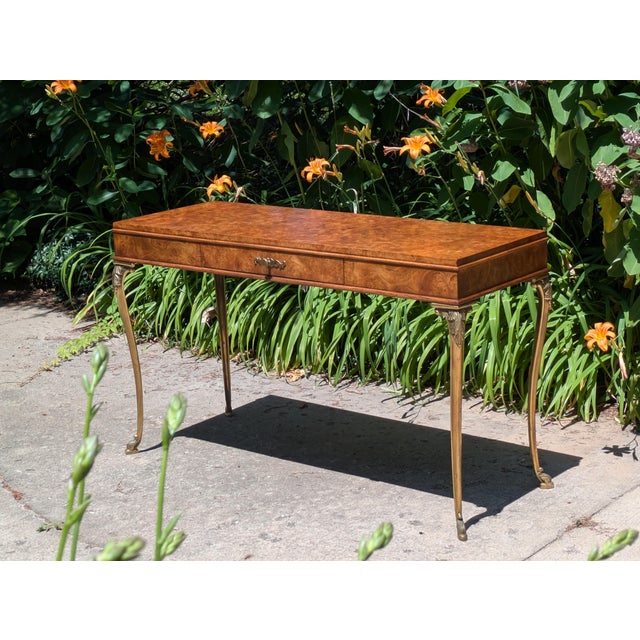 Featured is a vintage French Empire style console table. The table is finished with a burl top and all four sides resting...