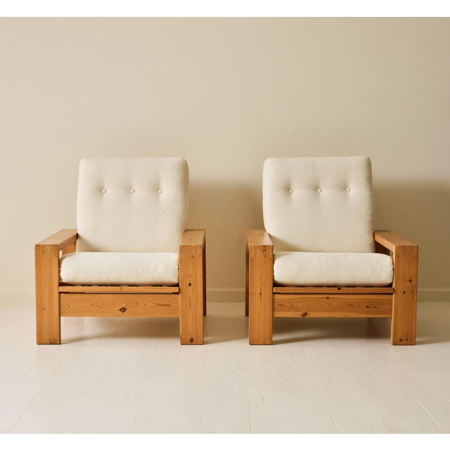 A pair of Scandinavian Modern lounge chairs crafted in solid pine and newly upholstered in textured ivory bouclé. The...