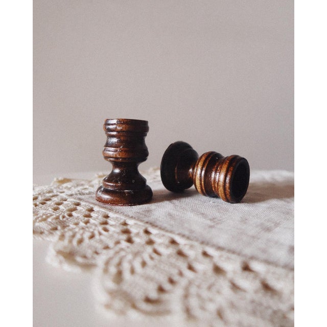 A pair of small-scale turned wood candlesticks with a compact, sculptural profile. Each features stacked ring detailing at...