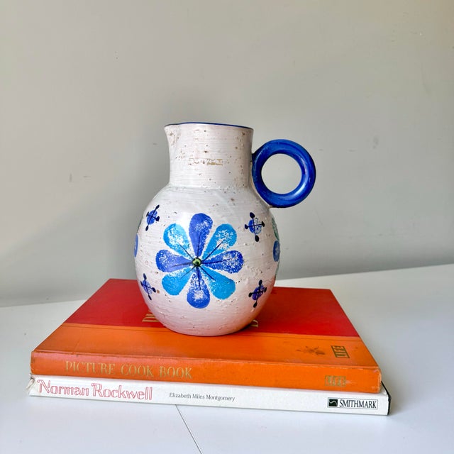 Vintage mid-century modern Bitossi pottery blue floral pitcher. The piece is hand painted with floral and starburst design.