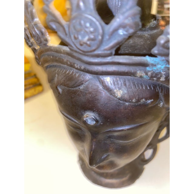 Hand-cast bronze head of a Buddhist bodhisattva in the Tibetan/Nepalese tradition. The figure features a serene closed-eye...