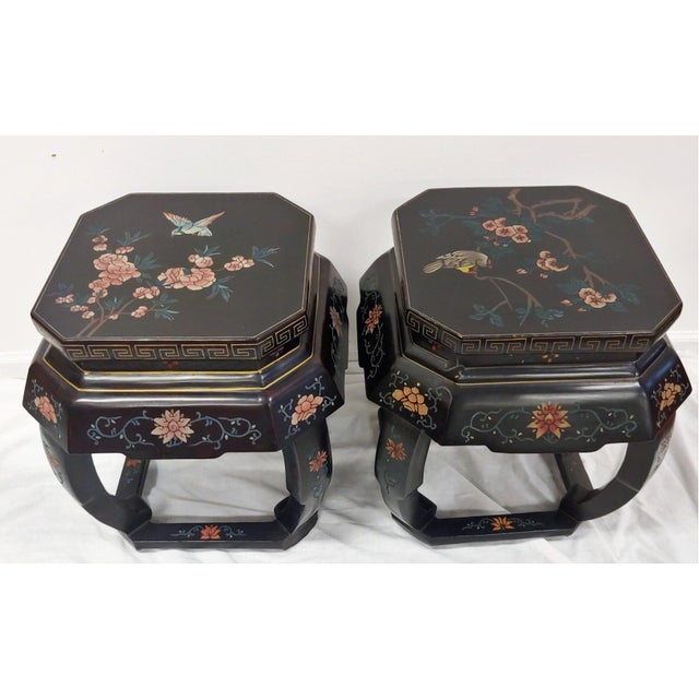 A pair of early 20th century black lacquered Chinese garden stools or low side tables with arched legs and stretchers...
