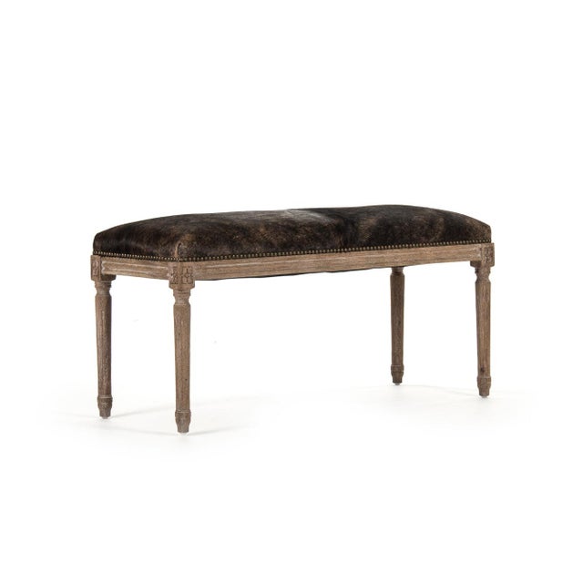 This is a bench featuring a sophisticated design with cowhide upholstery and an oak wood frame. The upholstery showcases a...