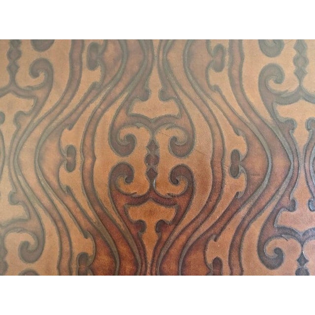 A substantial rectangular ottoman upholstered in richly embossed leather, mid-20th century. The warm brown leather...