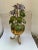 Vintage Italian tole flower sculpture in a stylized footed pot with twisted metal handle. Paint decorated and gold gilt...