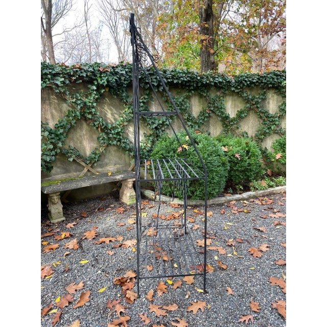 A black patinated iron baker’s rack in the French style. It has pot hangers as well as wine holders in the center. The...