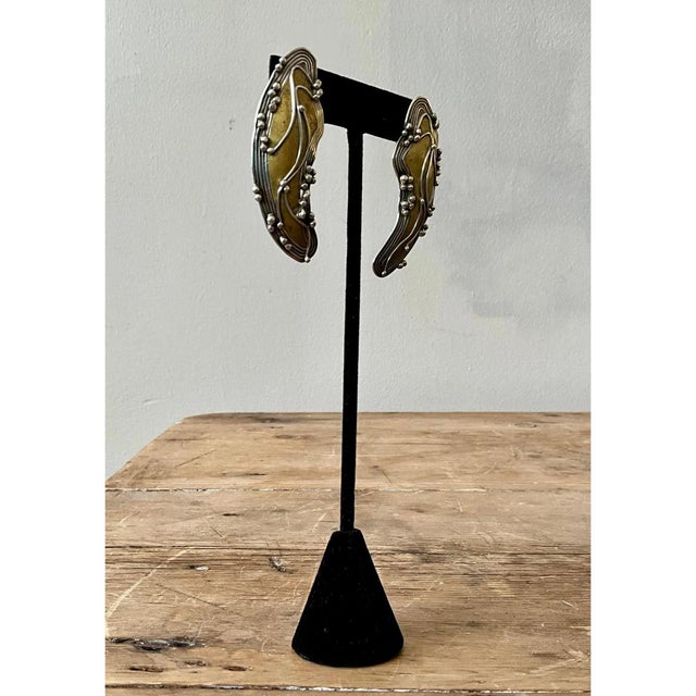 These vintage earrings are sweeping, crescent-shaped sculptures that curve like a wave or a ripple of water, narrowing to...