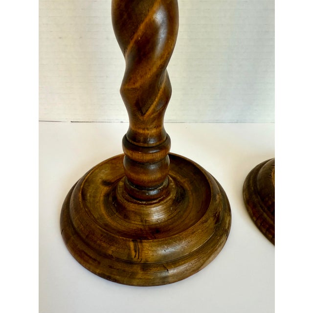This pair of early 20th century turned wood candlesticks features classic barley twist stems and substantial round bases....