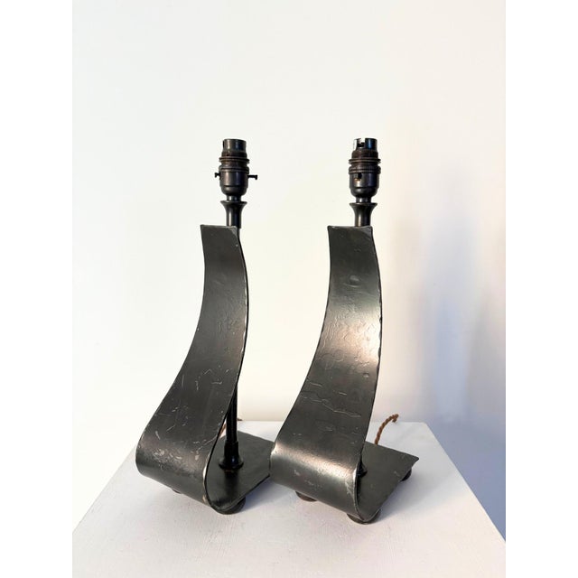 A pair of wrought iron table lamps with a fluid asymmetric design. These accent lights are handmade and feature a ribbon...