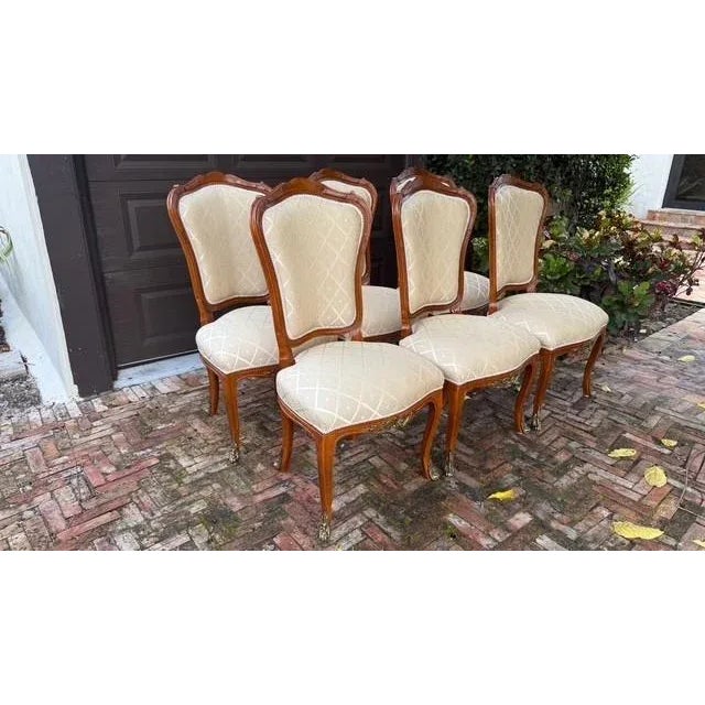 A refined and timeless set of six Louis XV–style dining chairs crafted by La Maison Élégante Pour Les Meubles Français....