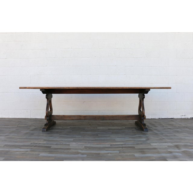 A beautiful 1940s French farmhouse dining table handcrafted from solid oak, featuring a timeless trestle base and a richly...