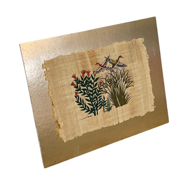 Signed decorative artwork depicting two birds in flight above stylized trees, foliage, and orange flowers. The composition...