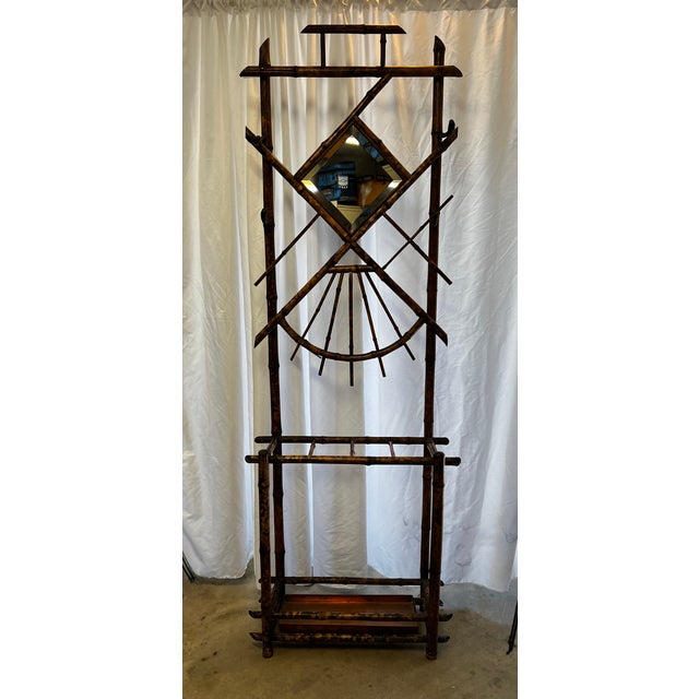 Stately bamboo hall tree with two glass shelves. One bamboo cross bar is missing. There are 4 horn style hooks for holding...