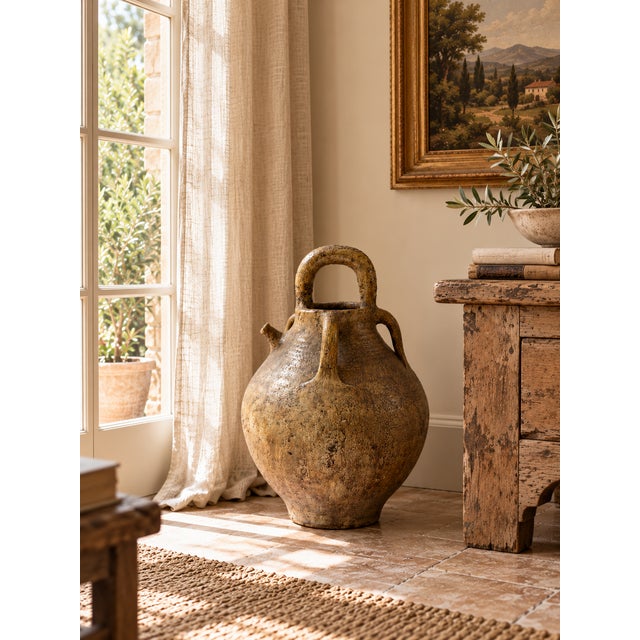 A distinctive antique French terracotta walnut oil jug, traditionally known as a cruche, featuring a rounded body, warm...