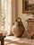 A distinctive antique French terracotta walnut oil jug, traditionally known as a cruche, featuring a rounded body, warm...