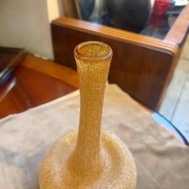 The yellow murano glass vase features a unique scavo (meaning "dug up" or "excavated") surface. This technique gives the...