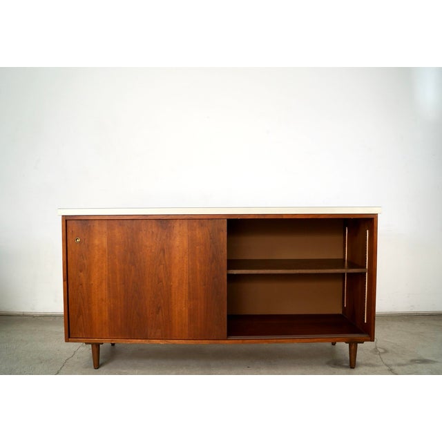 Vintage original Mid century Modern sliding door credenza for sale. It has two sliding doors that open up to an adjustable...