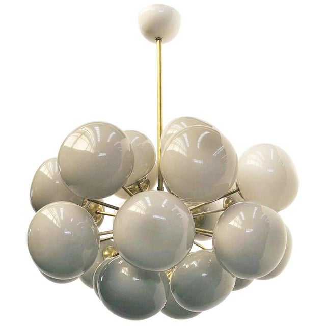 Italian oval shaped chandelier with 24 Murano pebble glass shades mounted on brass frame in unlacquered natural brass...