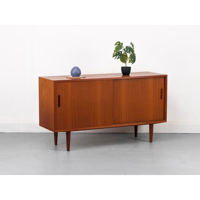 Compact and practical teak sideboard with two smooth-running sliding doors featuring stylish recessed handles. The...